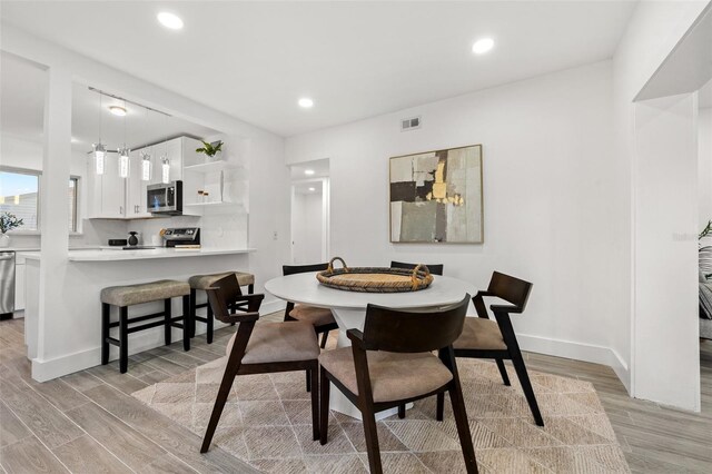 dining area featuring light wood-style floors, recessed lighting, visible vents, and baseboards