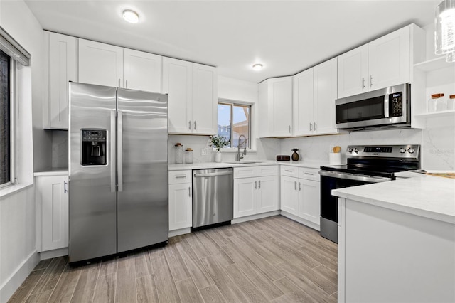 kitchen featuring white cabinets, decorative backsplash, stainless steel appliances, and a sink