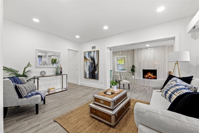 living area with baseboards, visible vents, light wood-type flooring, a fireplace, and recessed lighting