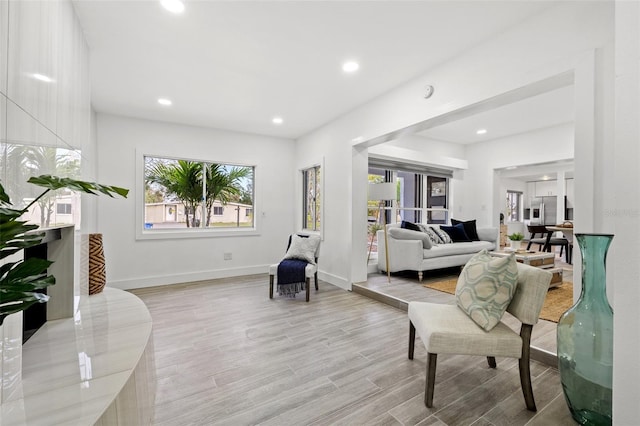 living area with baseboards, light wood-type flooring, and recessed lighting