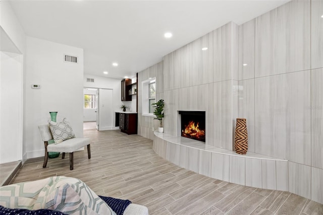 living room featuring wood tiled floor, visible vents, a fireplace, and recessed lighting