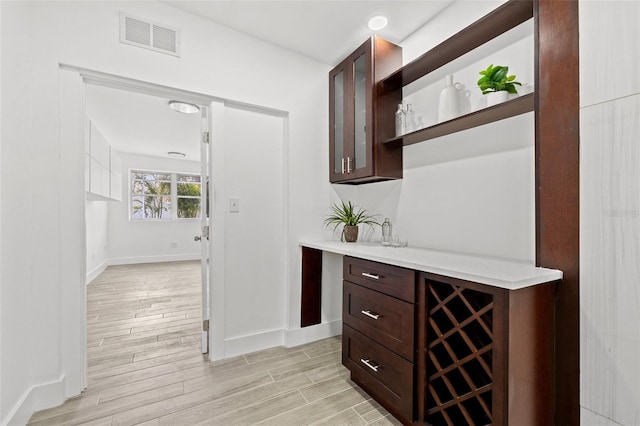 bar featuring baseboards, visible vents, beverage cooler, and wood finish floors