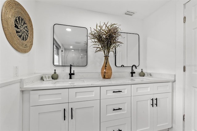 bathroom featuring double vanity, visible vents, walk in shower, and a sink