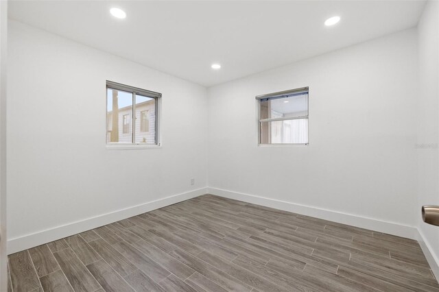 unfurnished room with baseboards, wood finished floors, and recessed lighting