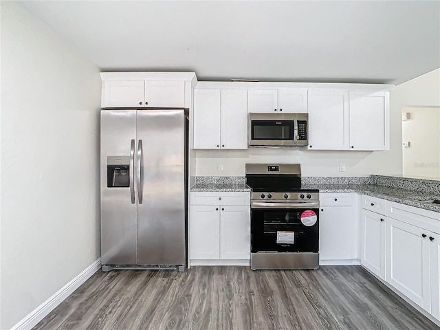 kitchen with dark stone countertops, appliances with stainless steel finishes, dark hardwood / wood-style flooring, and white cabinets