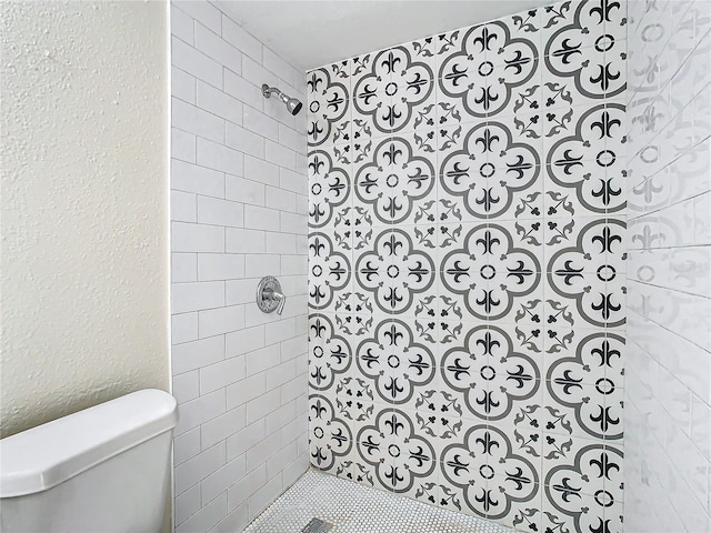 bathroom featuring a tile shower and toilet