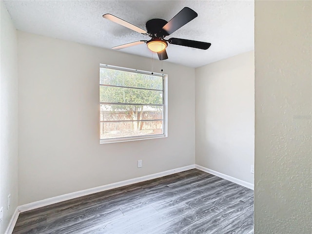 empty room with ceiling fan, dark wood-type flooring, and a textured ceiling