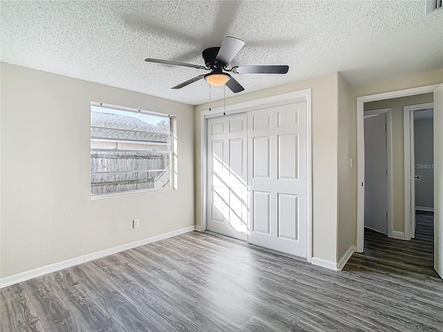 unfurnished bedroom with a textured ceiling, dark wood-type flooring, a closet, and ceiling fan