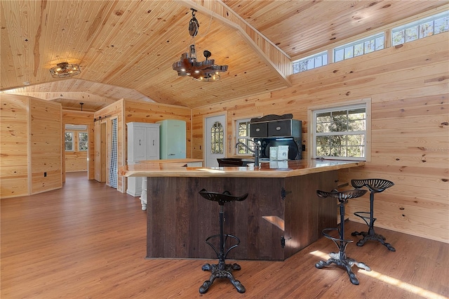 kitchen featuring vaulted ceiling, wooden walls, wood-type flooring, sink, and wooden ceiling