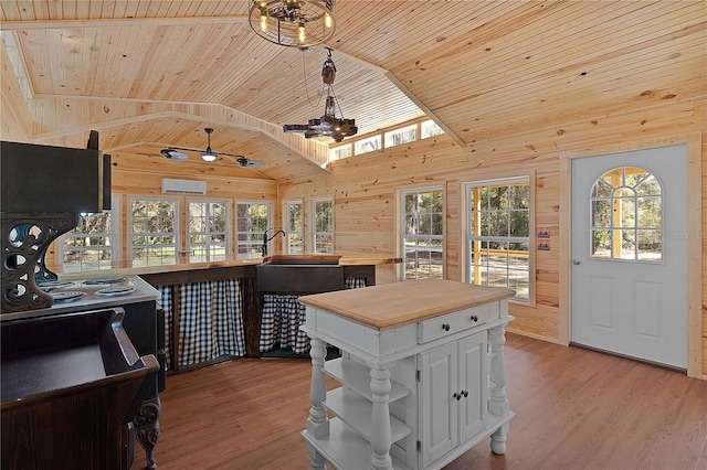 kitchen featuring wood walls, wood ceiling, white cabinetry, vaulted ceiling with skylight, and light hardwood / wood-style floors