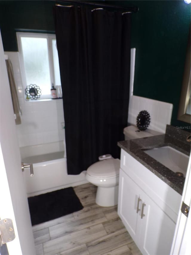 full bathroom with vanity, hardwood / wood-style floors, shower / tub combo with curtain, and toilet