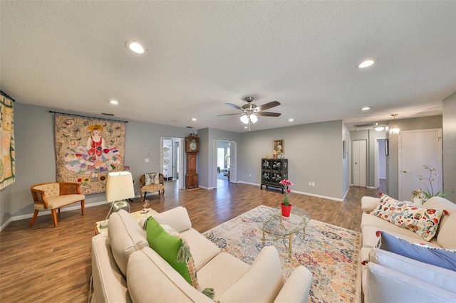 living room with a textured ceiling, wood-type flooring, and ceiling fan