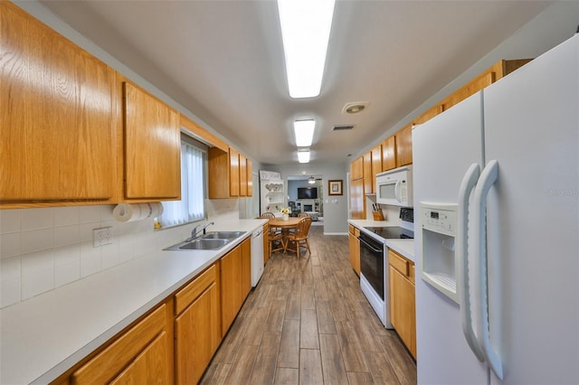 kitchen with wood-type flooring, sink, and white appliances