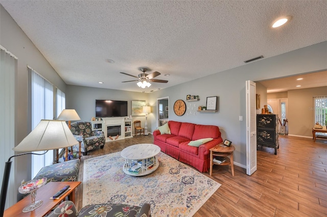 living room with wood-type flooring, ceiling fan, and a textured ceiling