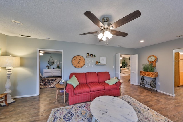 living room featuring ceiling fan and a textured ceiling