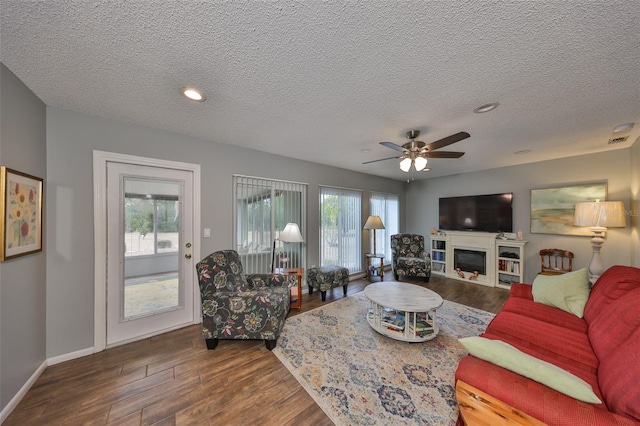 living room with hardwood / wood-style flooring, ceiling fan, and a textured ceiling