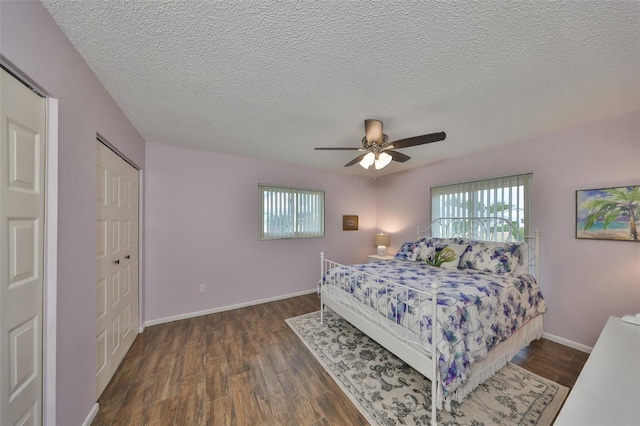 bedroom featuring dark hardwood / wood-style flooring, a textured ceiling, multiple windows, and ceiling fan