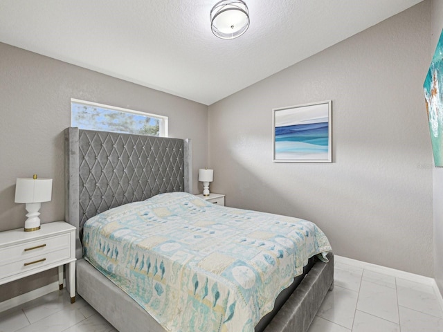 bedroom featuring lofted ceiling and a textured ceiling