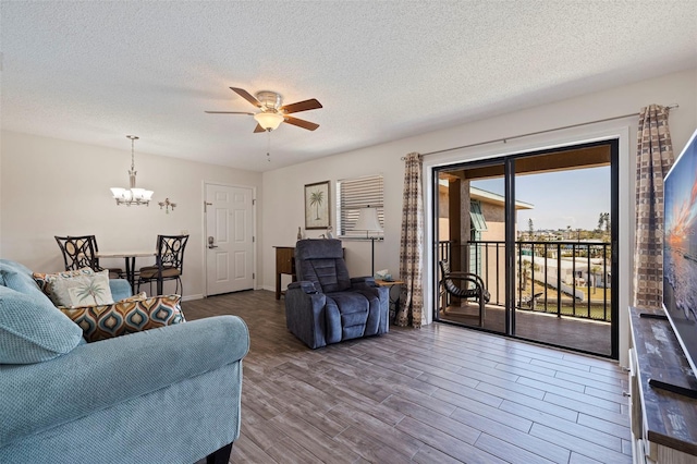 living room with hardwood / wood-style flooring, ceiling fan with notable chandelier, and a textured ceiling