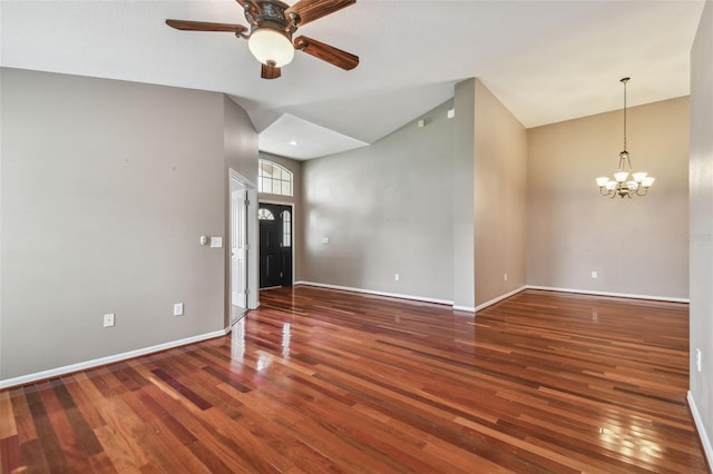 interior space with a towering ceiling, dark hardwood / wood-style floors, and ceiling fan with notable chandelier