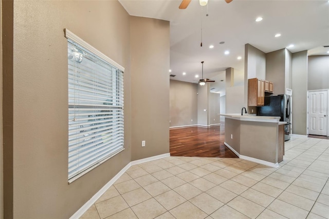 kitchen featuring decorative light fixtures, light tile patterned floors, black refrigerator, kitchen peninsula, and ceiling fan