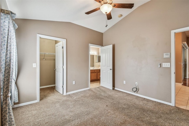 unfurnished bedroom with lofted ceiling, a spacious closet, ceiling fan, light carpet, and a closet