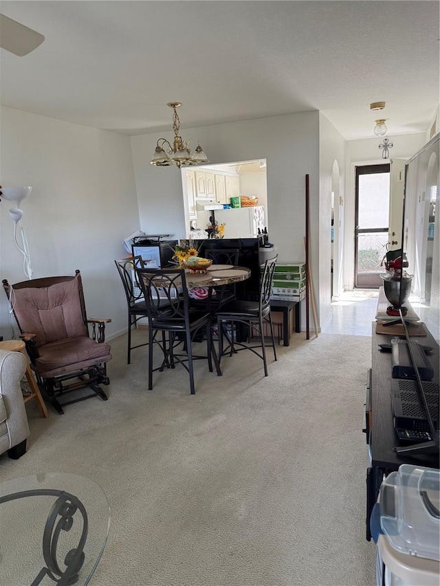 dining space featuring light colored carpet and a notable chandelier