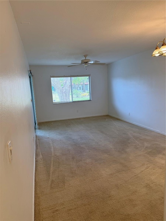 carpeted spare room with ceiling fan and baseboards