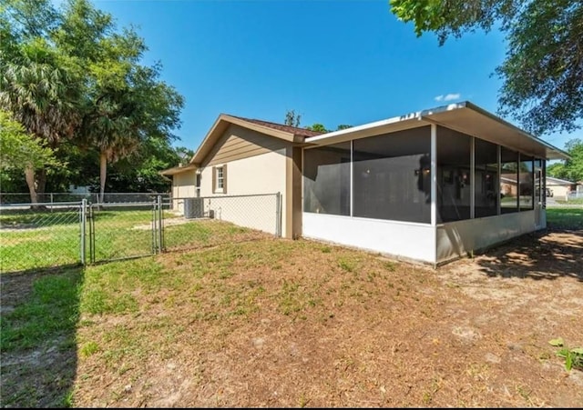 view of side of property with central AC, a lawn, and a sunroom