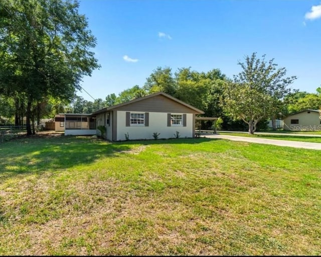 view of home's exterior with a sunroom and a lawn