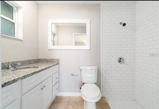 bathroom with a tile shower, vanity, tile patterned floors, and toilet