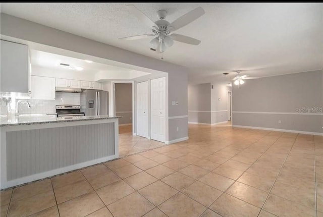 kitchen with light tile patterned floors, appliances with stainless steel finishes, backsplash, white cabinets, and kitchen peninsula