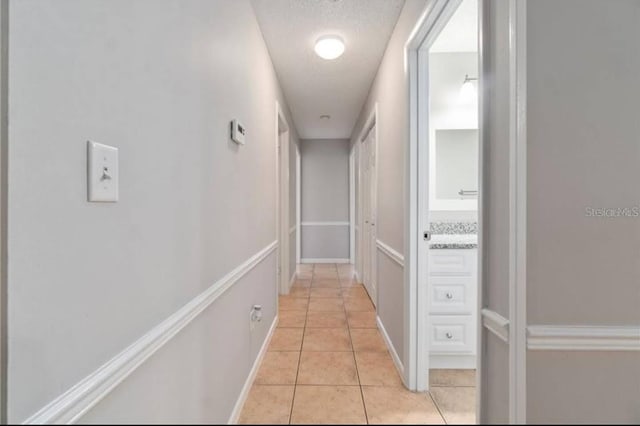 hallway with light tile patterned floors and a textured ceiling