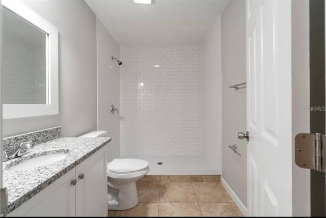 bathroom with vanity, toilet, tile patterned flooring, and a tile shower