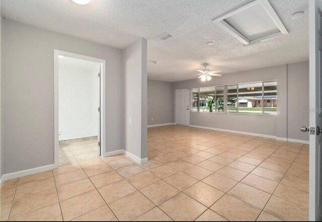 spare room with ceiling fan, light tile patterned floors, and a textured ceiling