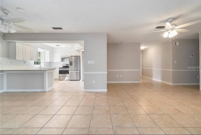 unfurnished living room featuring light tile patterned floors, a textured ceiling, and ceiling fan