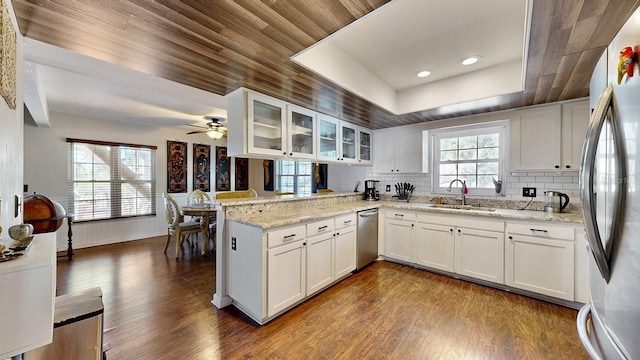 kitchen featuring sink, stainless steel appliances, light stone countertops, white cabinets, and kitchen peninsula