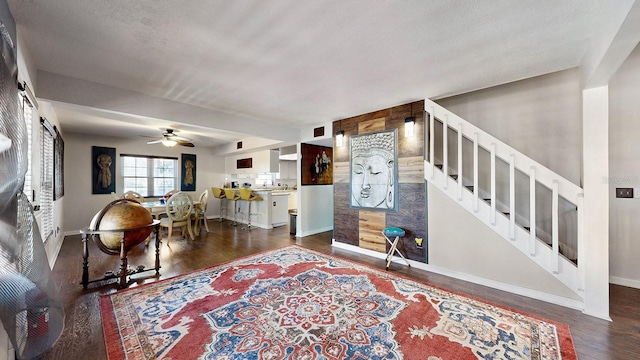 living room with ceiling fan, dark hardwood / wood-style floors, and a textured ceiling