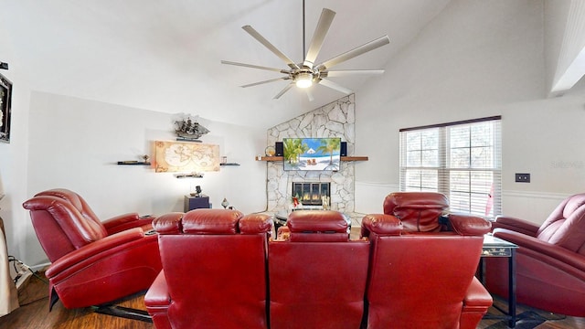 living room featuring ceiling fan, lofted ceiling, a stone fireplace, and wood-type flooring