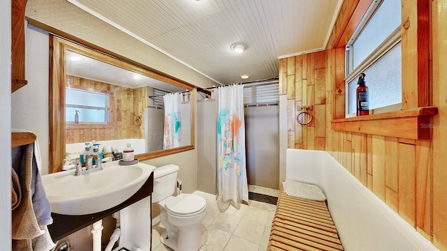 bathroom featuring sink, tile patterned floors, wooden walls, and toilet