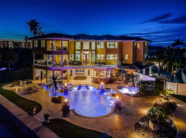 pool at dusk featuring an in ground hot tub and a patio area