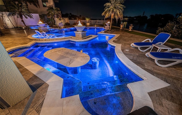 pool at twilight with an in ground hot tub and a patio