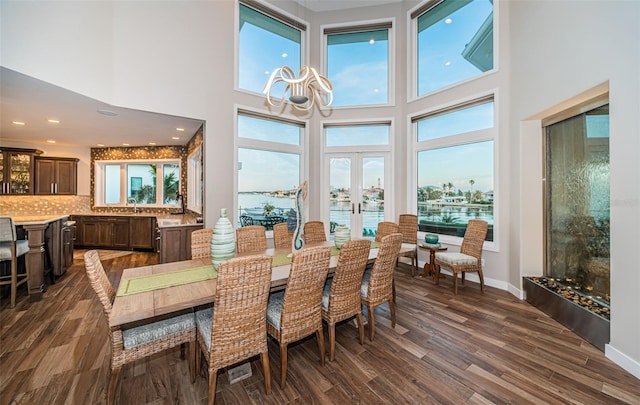 dining area with a water view, a healthy amount of sunlight, and dark hardwood / wood-style floors