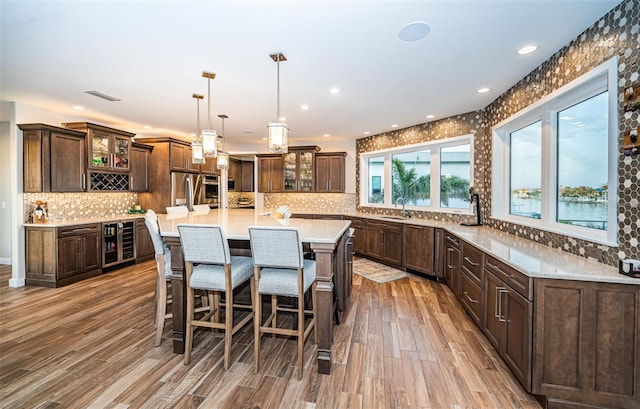 kitchen featuring pendant lighting, sink, wine cooler, a large island with sink, and fridge