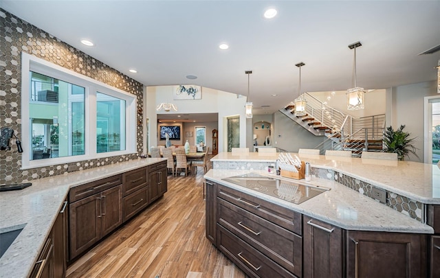 kitchen with pendant lighting, black electric stovetop, light stone countertops, light hardwood / wood-style floors, and a kitchen island