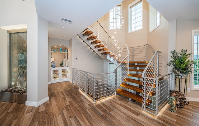 staircase featuring hardwood / wood-style flooring and a towering ceiling