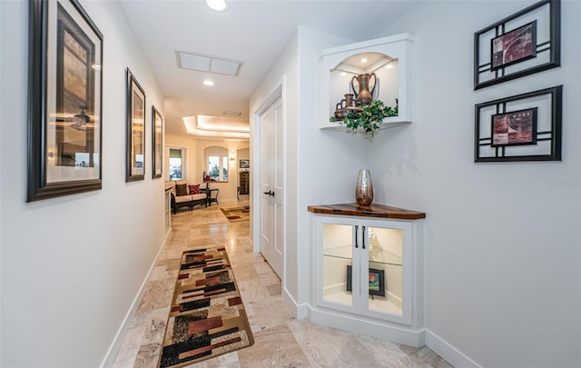 hall featuring a tray ceiling