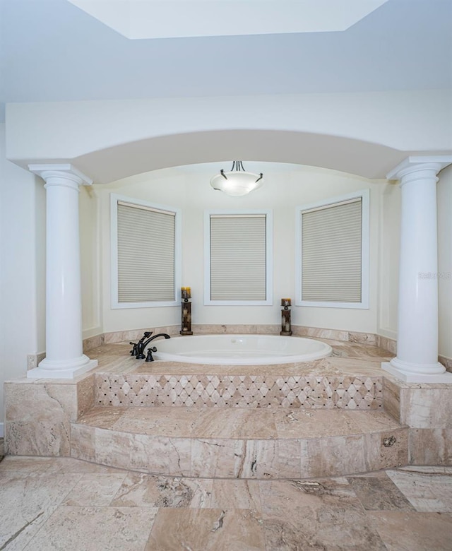 bathroom with decorative columns and tiled bath