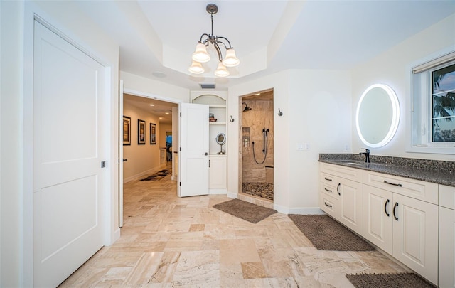 bathroom featuring a chandelier, a tile shower, vanity, a raised ceiling, and built in features