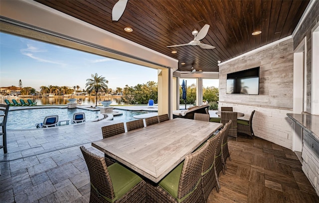 view of patio featuring a water view, ceiling fan, a fenced in pool, and an outdoor bar